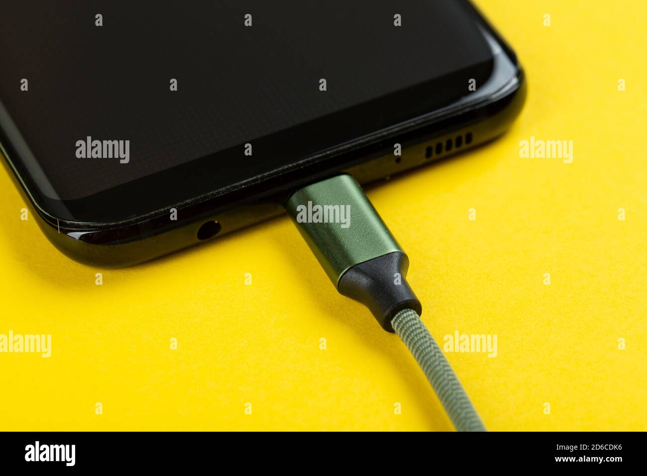 Charging a mobile phone on a yellow background. Stock Photo