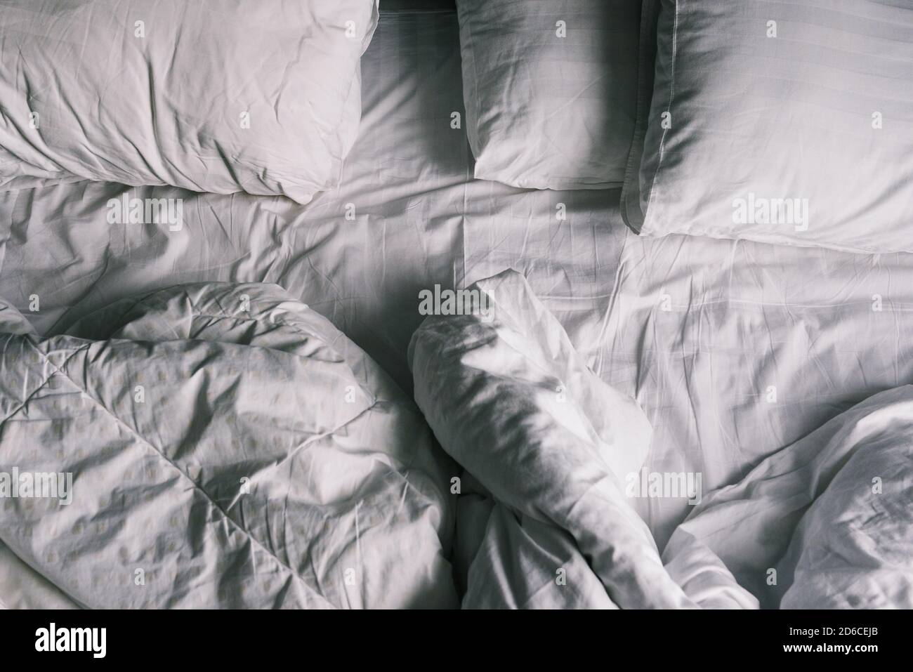 Unmade bed. Rumpled sheets and pillows after a night's sleep. The view from the top. Dirty white bed linen Stock Photo