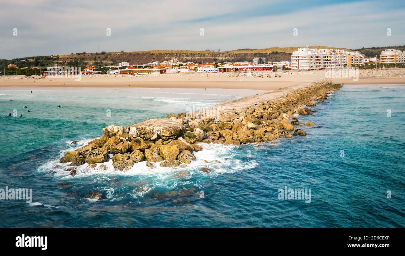 Rocky pier or breakwater on the sandy beach. Costa Da Caparica Stock Photo