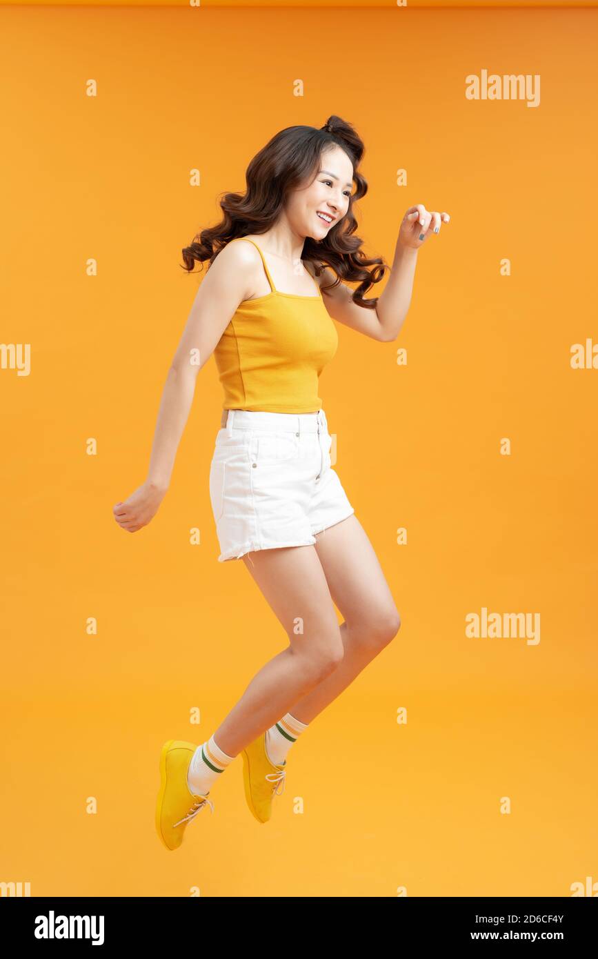 Full length portrait of a smiling pretty woman jumping isolated on a ...