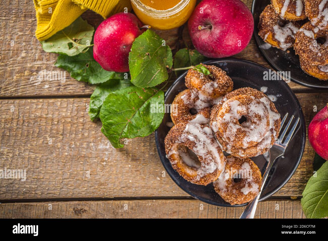 Autumn sweet dessert recipe. Homemade apple cider donuts. Baked donuts with sugar, cinnamon glaze and white sugar topping drizzle, on wooden backgroun Stock Photo