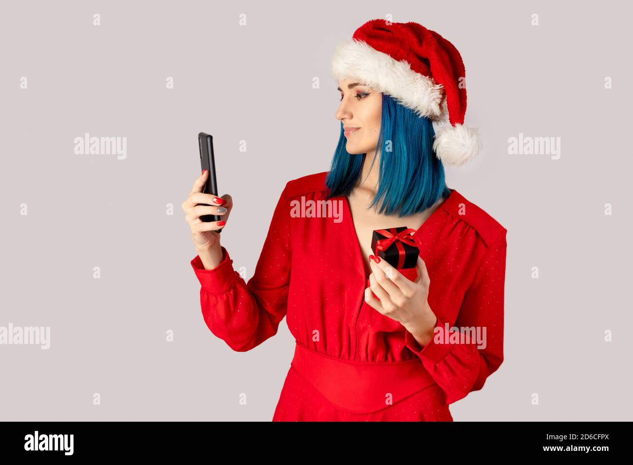 Happy young woman in santa hat with gift box and smartphone Stock Photo ...