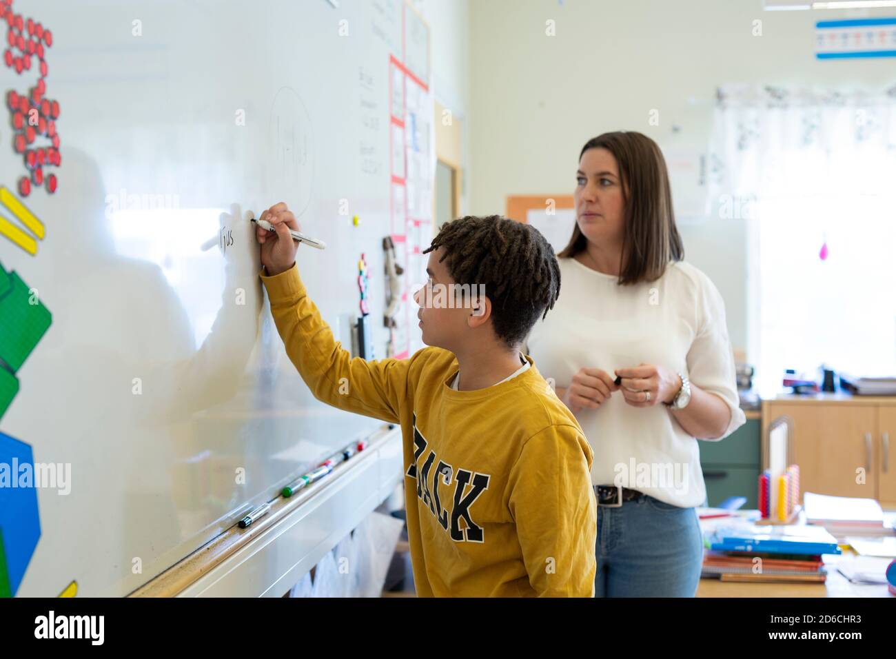 Boy writing on whiteboard in classroom Stock Photo - Alamy