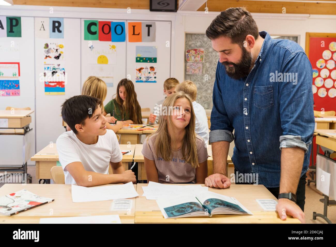 Teacher helping children in classroom Stock Photo - Alamy