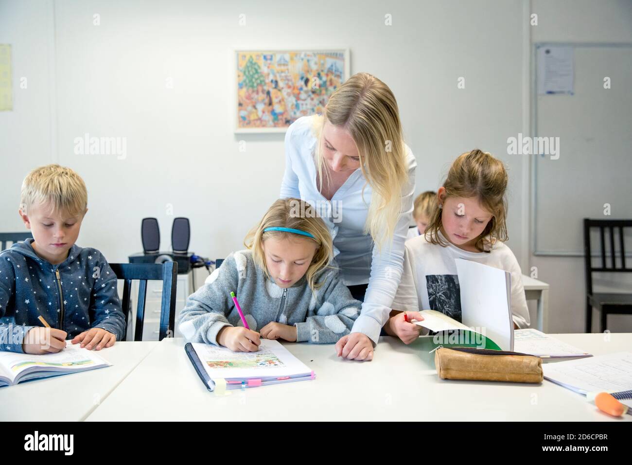 Teacher helping children in classroom Stock Photo - Alamy