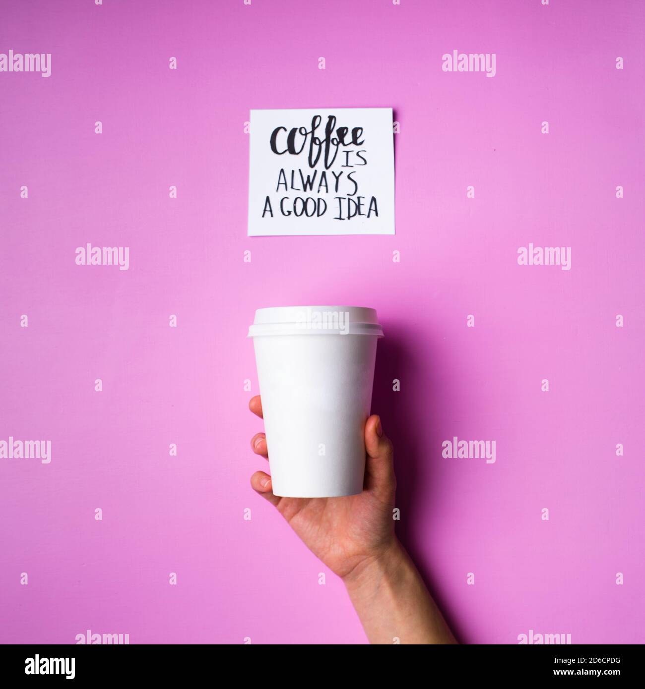 Paper cup in human hand and card with inscription on pink background Stock Photo