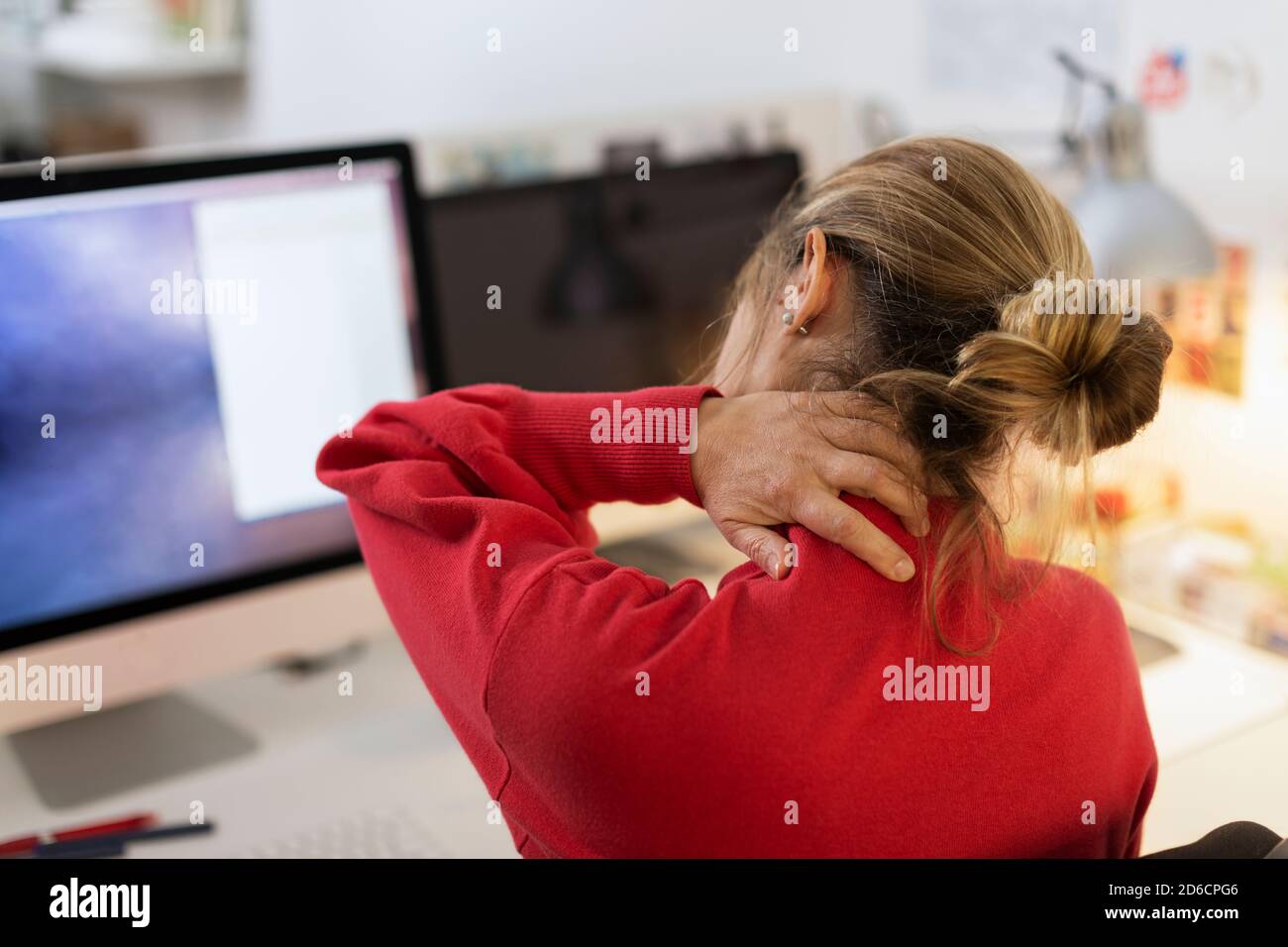 Woman massaging her neck at desk Stock Photo - Alamy