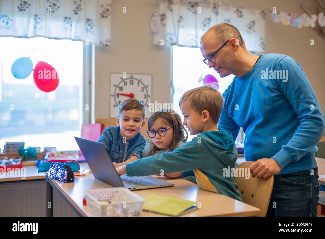 Teacher helping children in classroom Stock Photo - Alamy