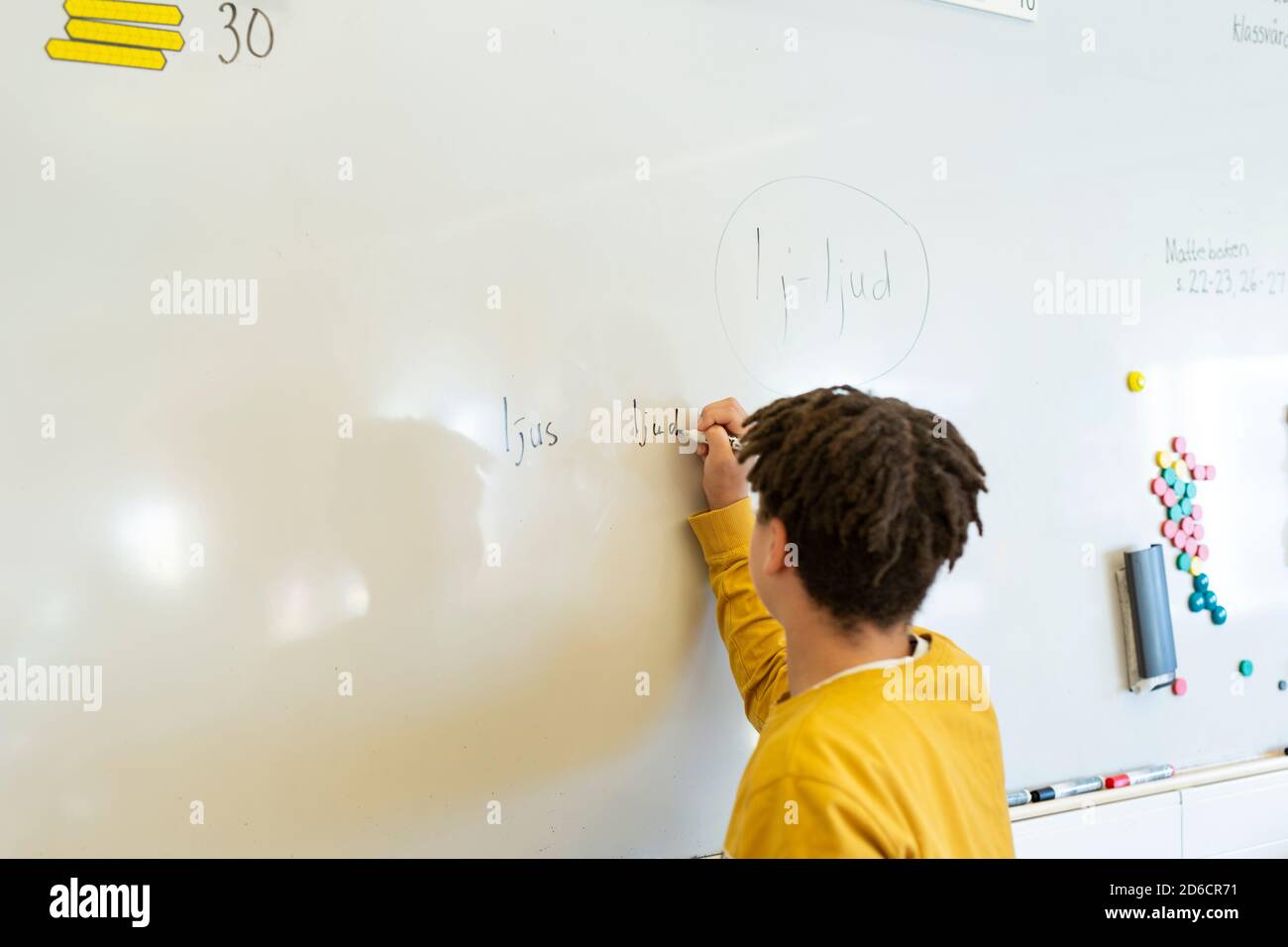 Boy writing on whiteboard in classroom Stock Photo - Alamy