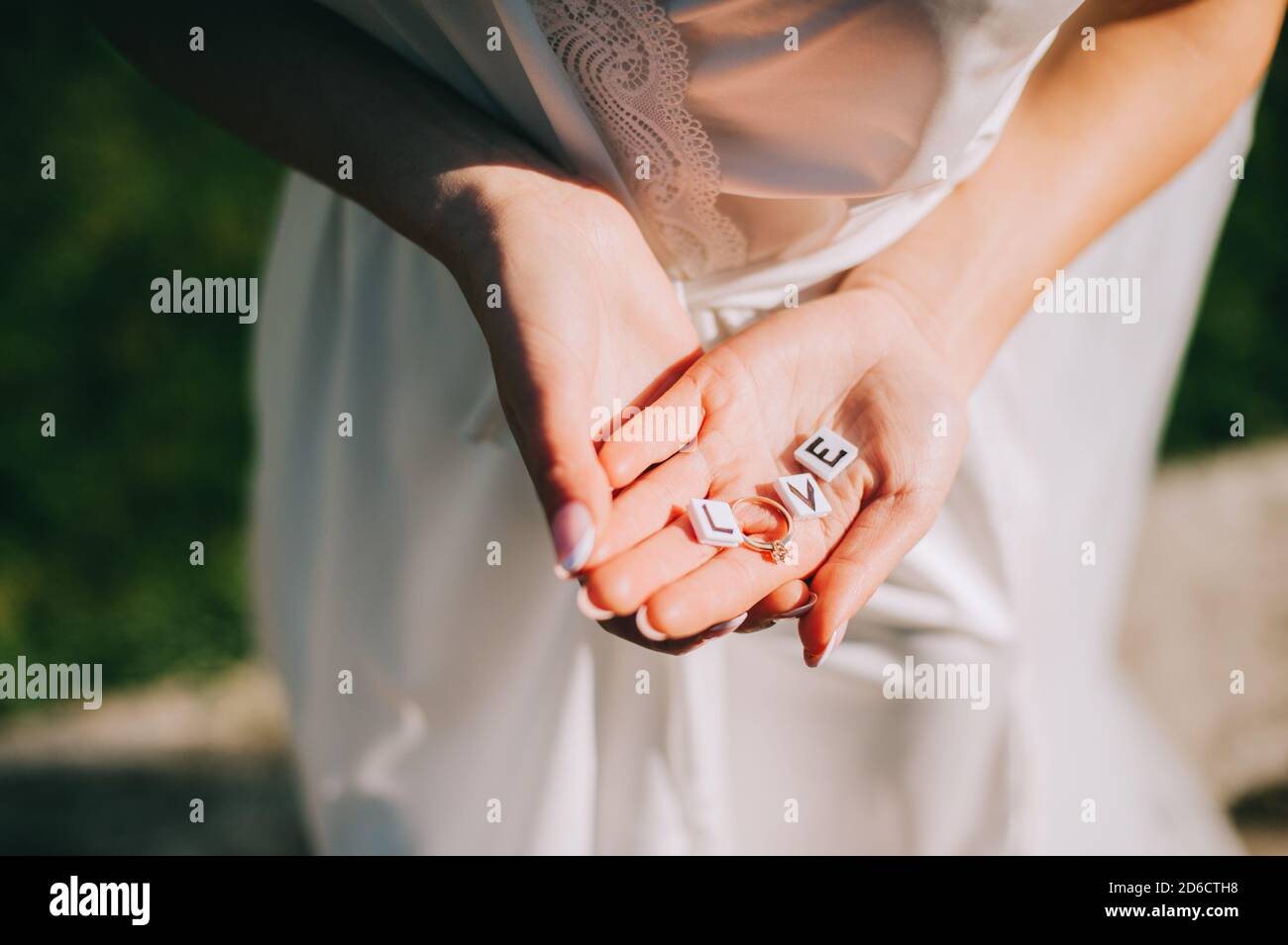 Bride in her hands holding a ring and small cubes with letters that form the inscription love Stock Photo