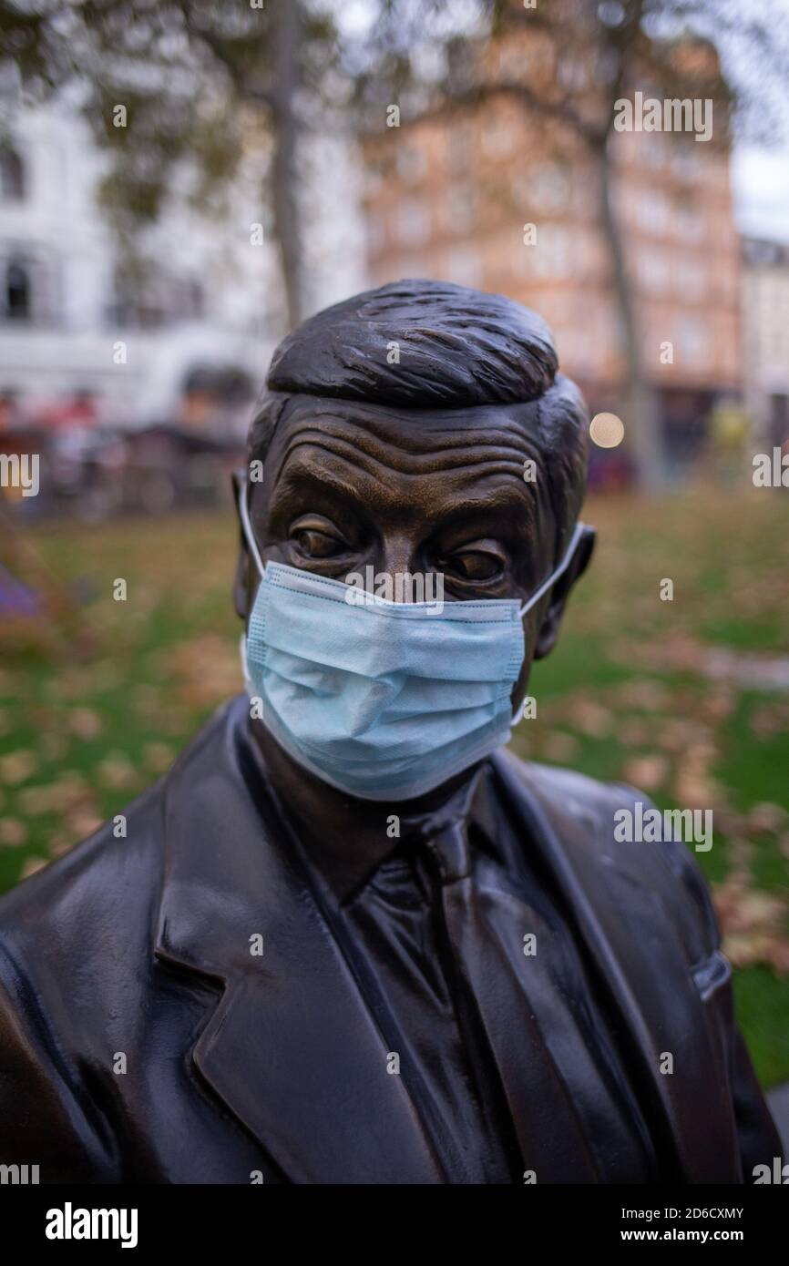 A bronze statue depicting a scene from a Mr Bean film featuring Rowan Atkinson wearing a protective mask during the COVID-19 pandemic sitting on a par Stock Photo