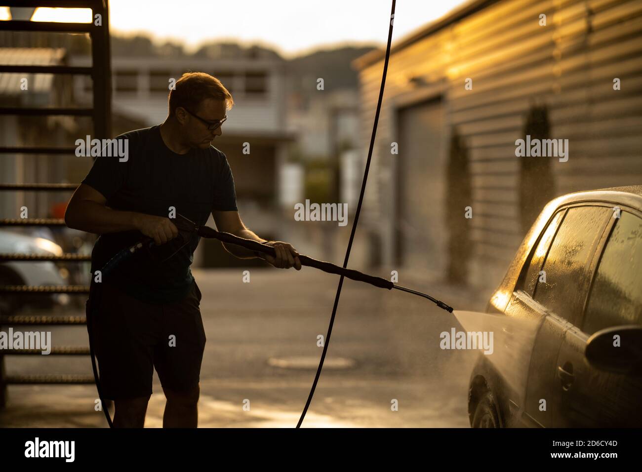 Young man washing his beloved car carefully in a manual car wash to