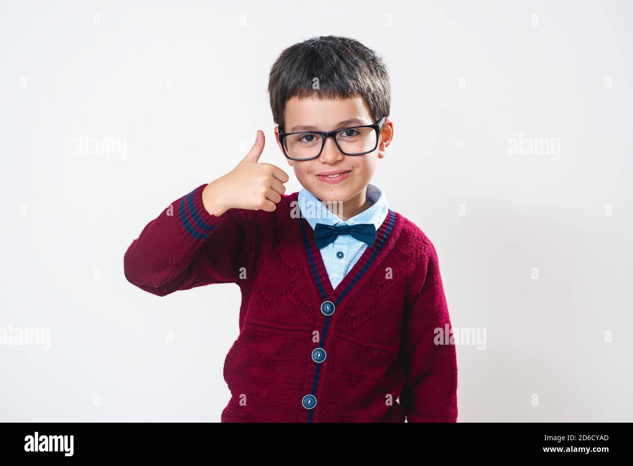 The schoolboy in a sweater and glasses smiles and shows a thumb up ...