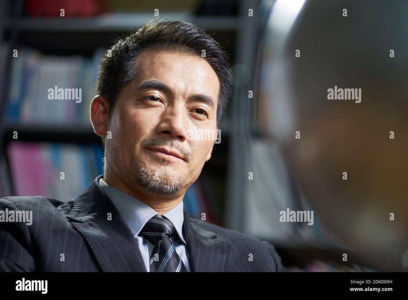 asian corporate executive looking at  a turning tellurian with confidence in office Stock Photo