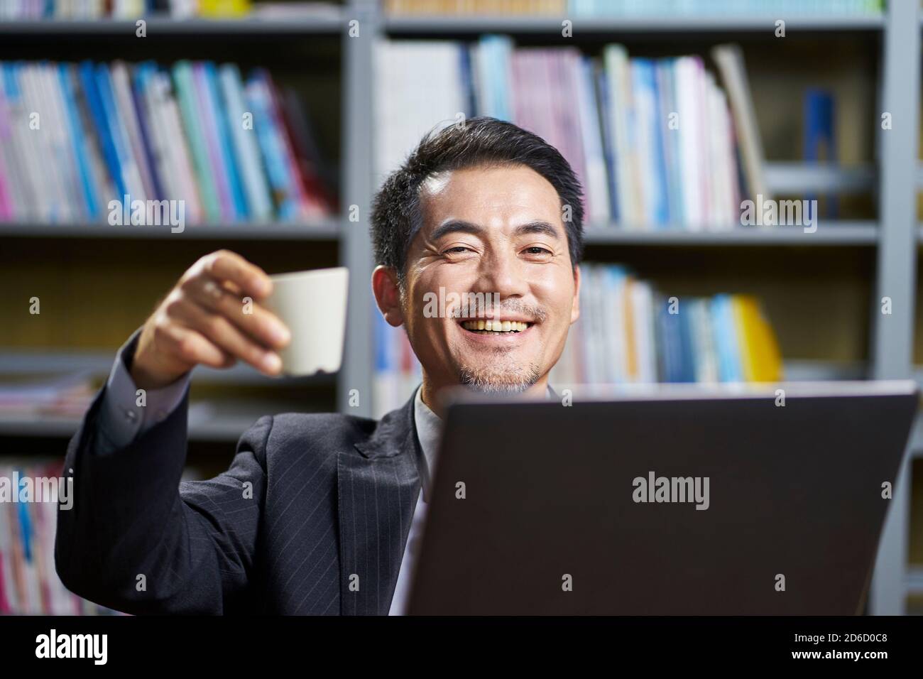happy asian corporate executive celebrating achievement and success with cup of coffee Stock Photo