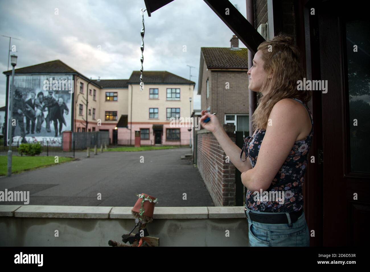 17.07.2019, Derry, Northern Ireland, United Kingdom - Young resident in the Catholic district of Bogside, in the back a Catholic mural reminiscent of Stock Photo