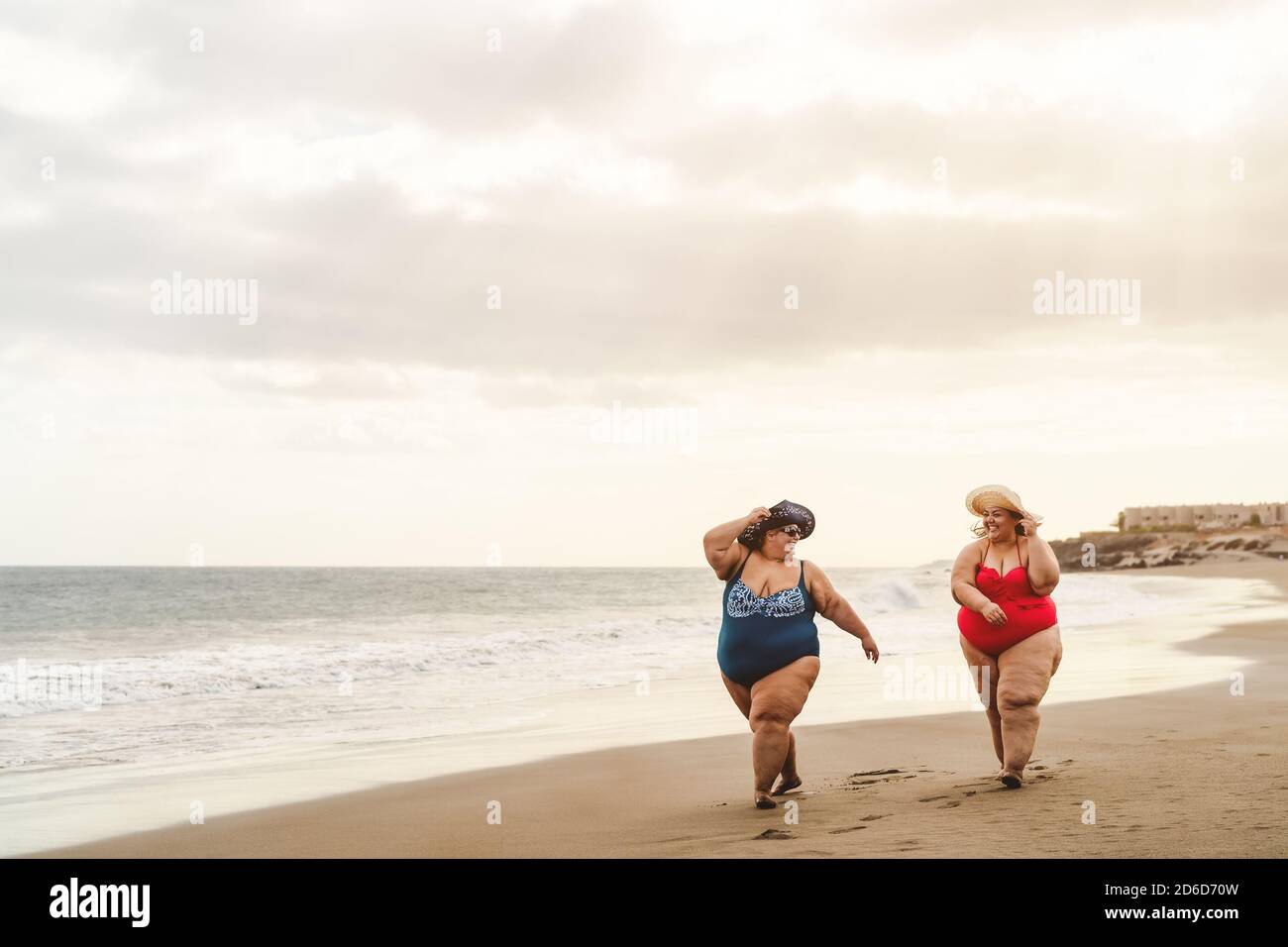 Happy plus size women having fun walking on the beach Curvy confident