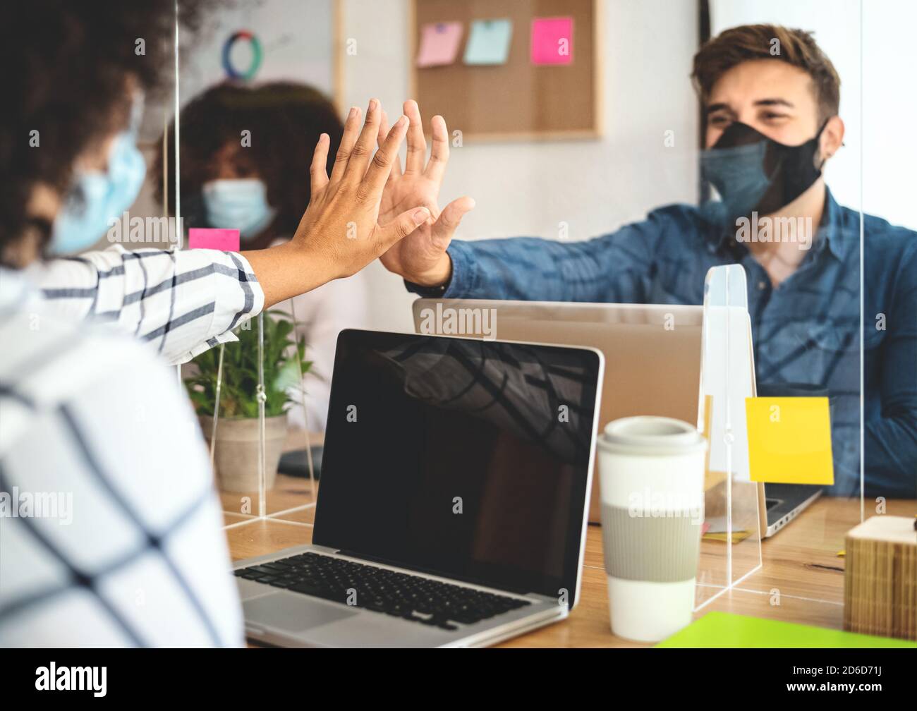 Young people in co-working creative space wearing surgical mask protection and keeping social distance to avoid corona virus spread Stock Photo