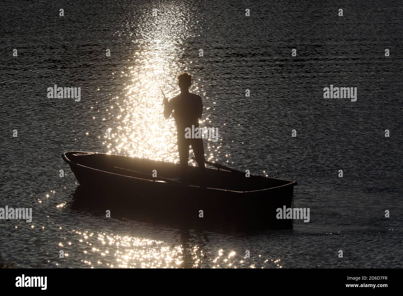 23.06.2020, Dranse, Brandenburg, Germany - Silhouette: Teenager in a boat is fishing in a lake in the evening. 00S200623D600CAROEX.JPG [MODEL RELEASE: Stock Photo