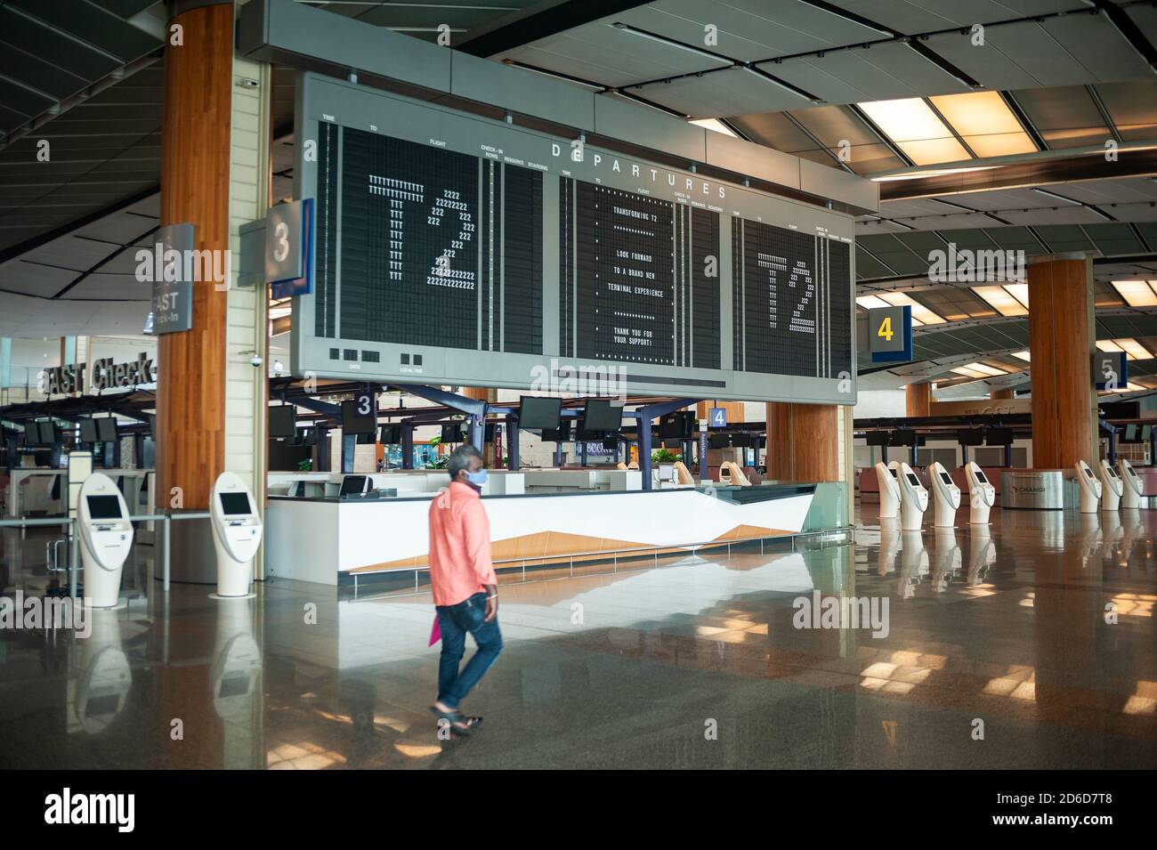 05.08.2020, Singapore, , Singapore - A man with a mouth guard walks past the scoreboard in the closed and empty departure hall in Terminal 2 at Changi Stock Photo