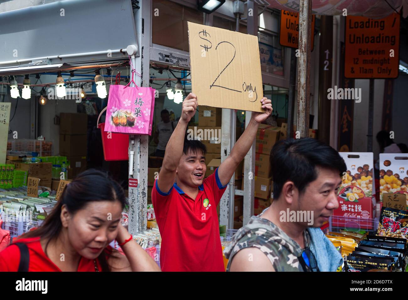 24.01.2020, Singapore, , Singapore - A salesman holds up a cardboard sign with a savings offer at the beginning of the Corona crisis, while people str Stock Photo