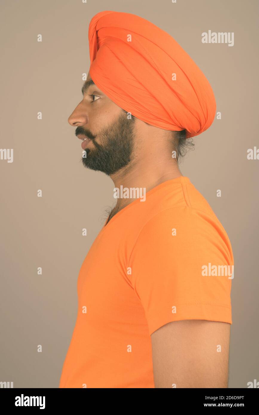 Young handsome Indian Sikh man wearing turban against gray background Stock Photo