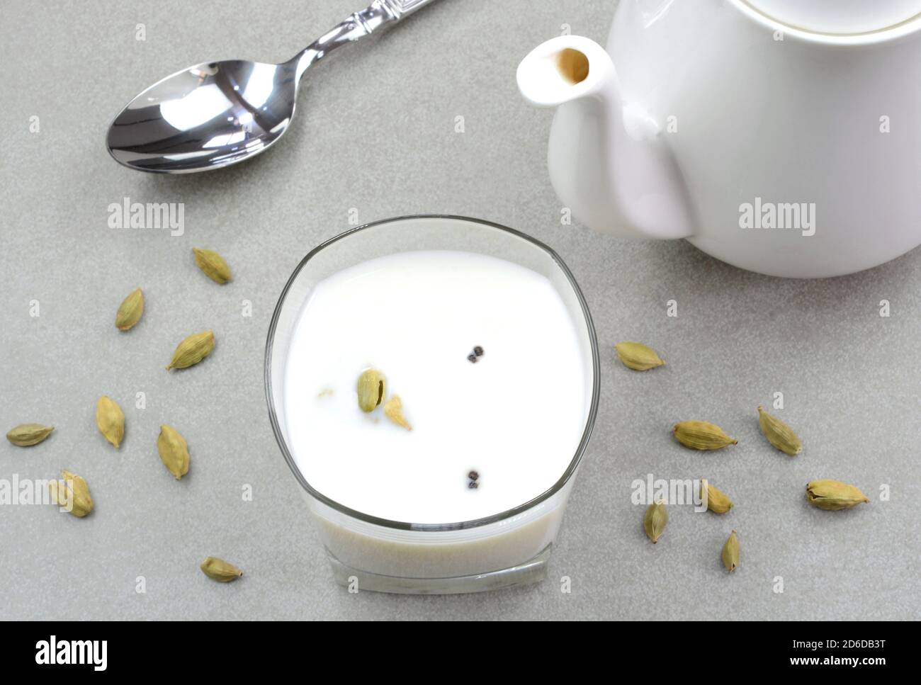 Hot cardamom milk in a glass cup with cardamom in the background Stock Photo