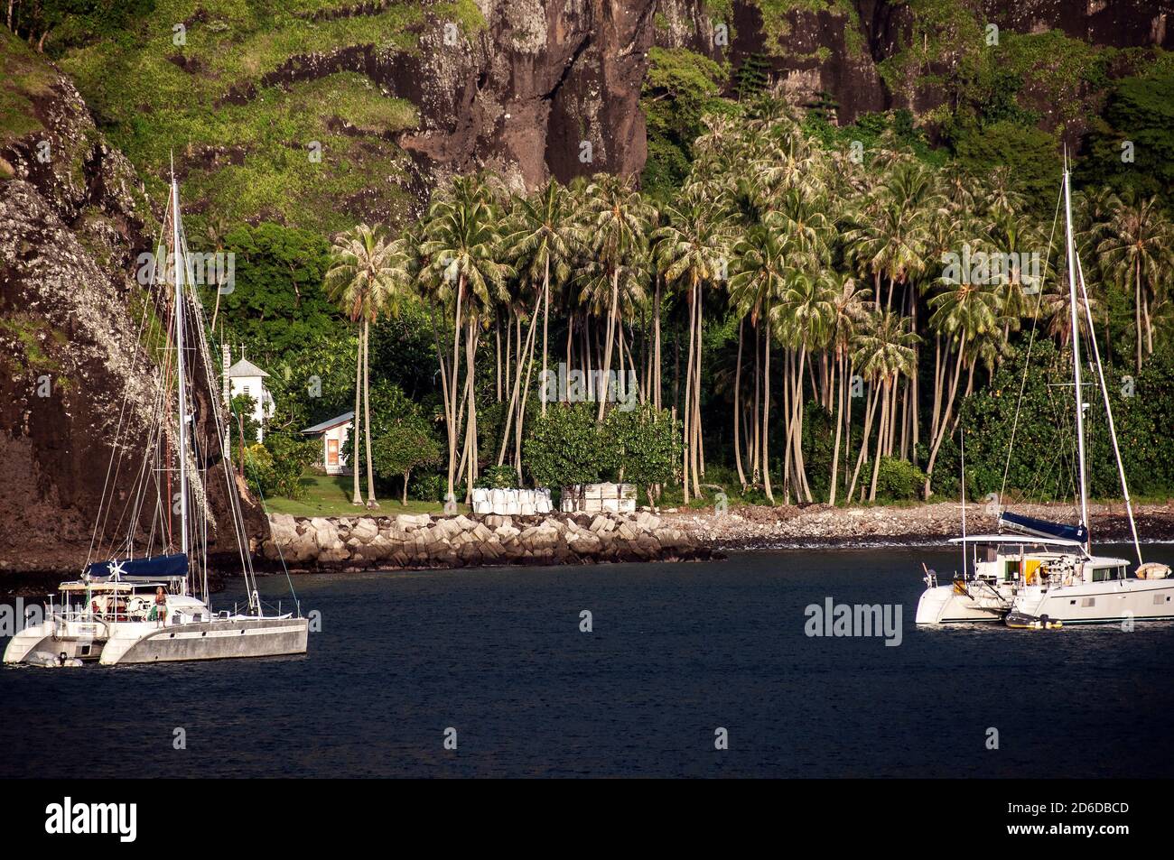 House on beach, anchored catamarans, Bay of Virgins, Hanaveve, Fatu Hiva Stock Photo