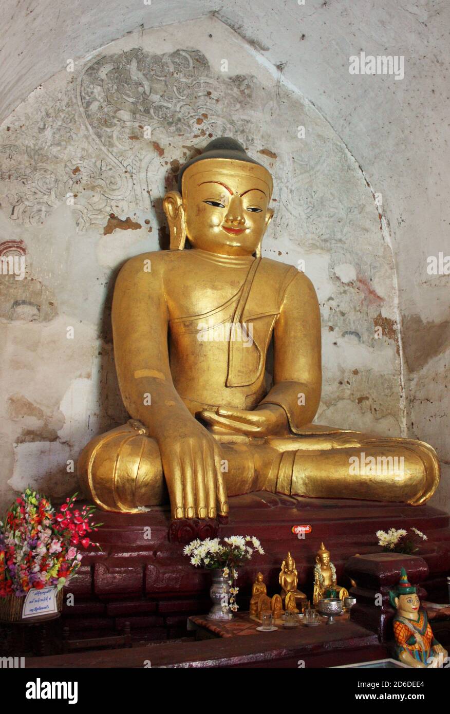 Gold color Buddha with flowers and smaller statues in foreground at