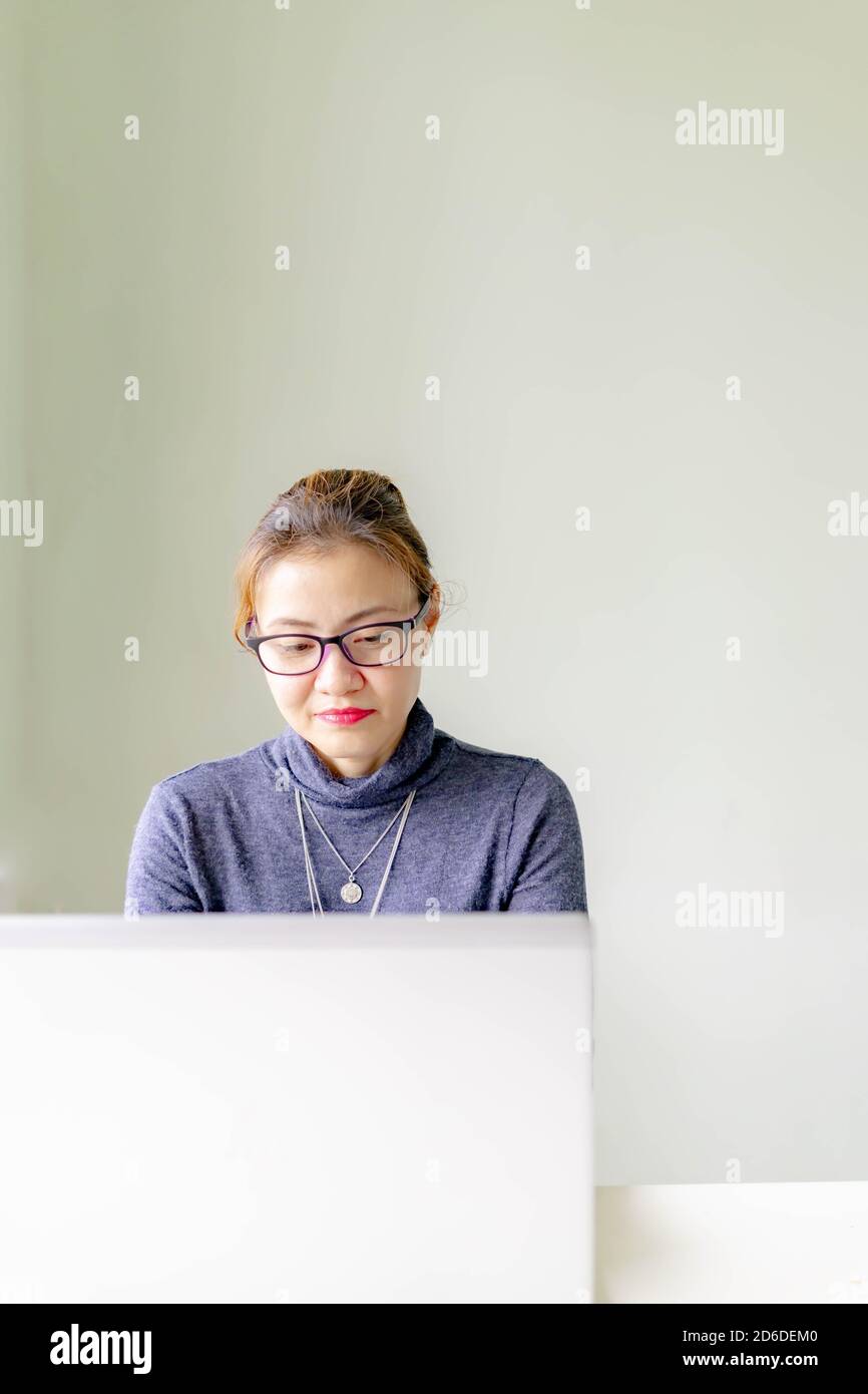 Young asian businesswoman using computer at home office workplace, happy korean employee working on laptop, attractive japanese or chinese woman stude Stock Photo