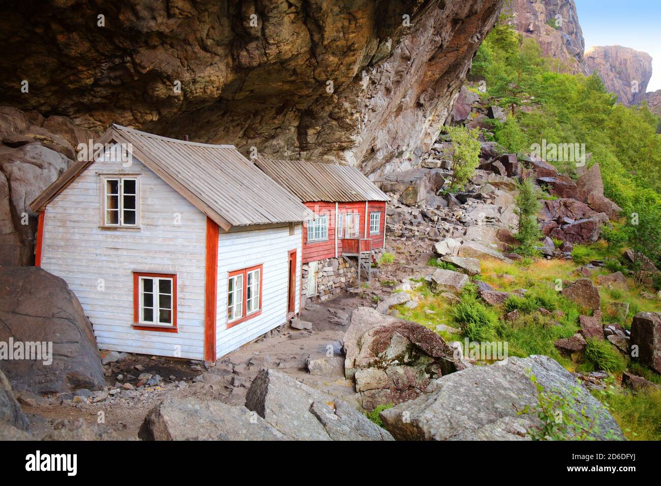 Norway landmark. Helleren old homes hidden beneath huge rock cliff in Jossingfjord. Stock Photo