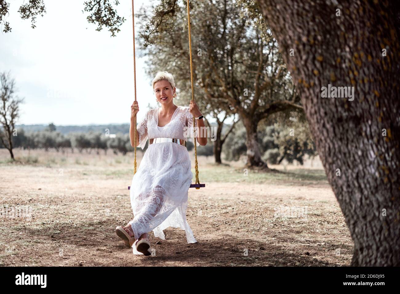Romantic pregnant woman on a swing among cork trees Stock Photo