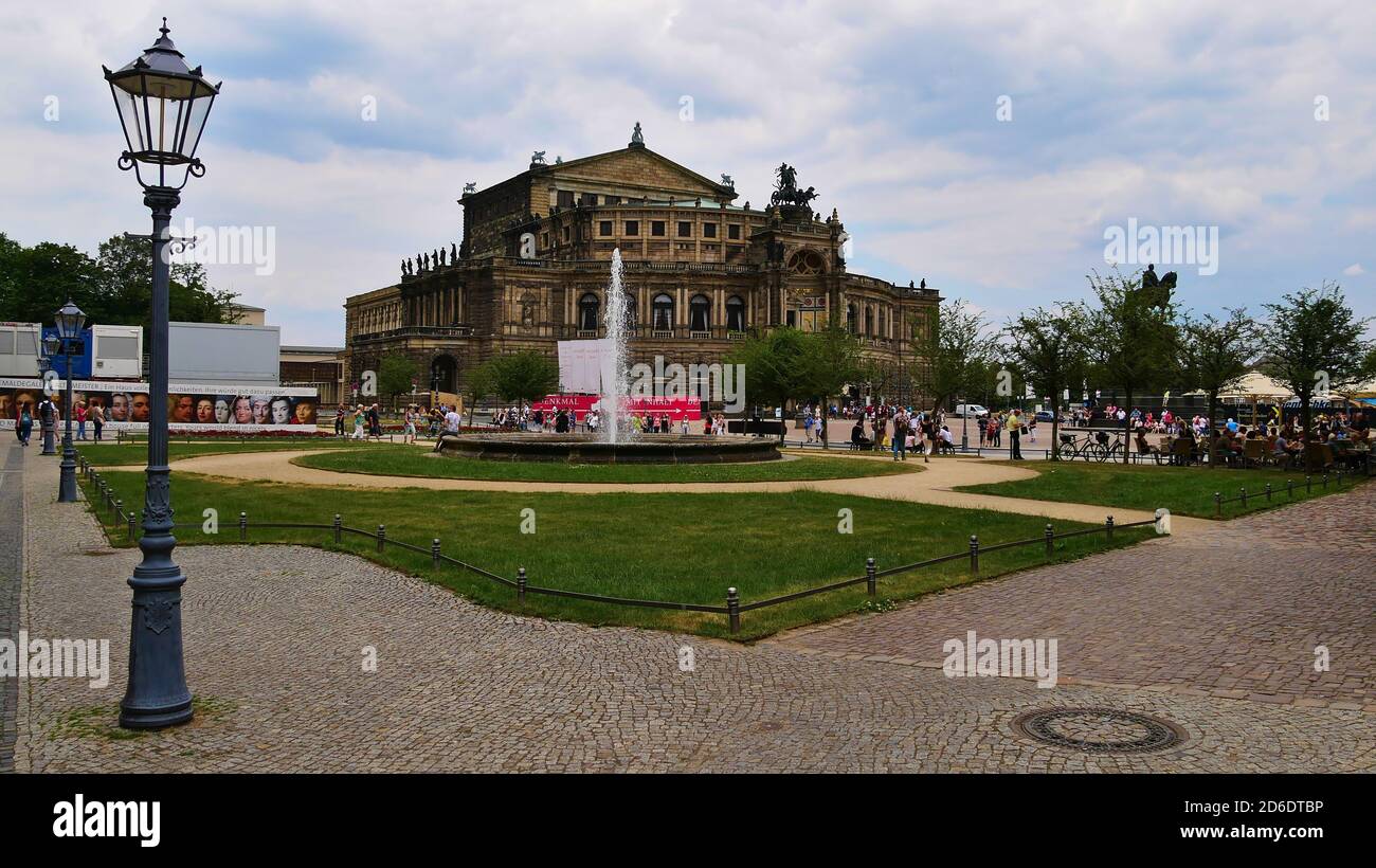 Dresden, Germany - 06/16/2018: Famous opera house Semperoper, originally built in the 19th century, with lantern, fountain and crowded square. Stock Photo
