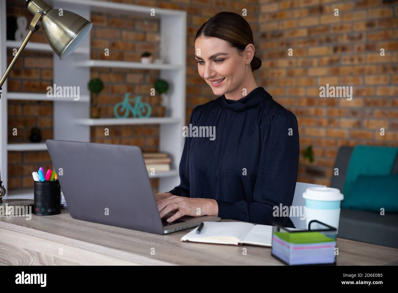 Woman using laptop while sitting on her desk Stock Photo - Alamy