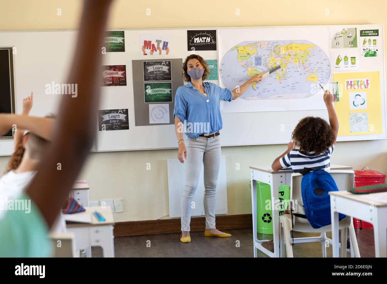 Female teacher wearing face mask teaching geography to students in class Stock Photo