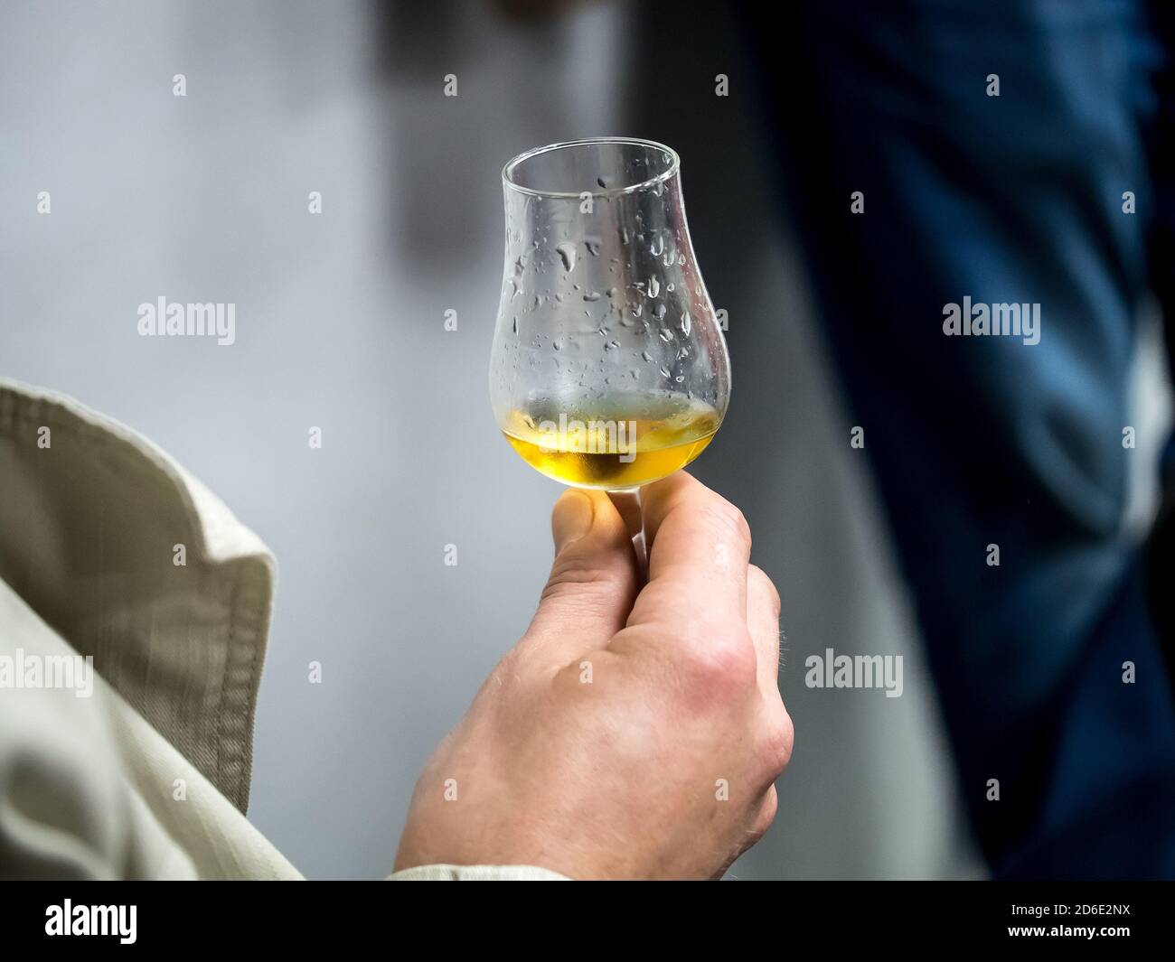 Hand holding a snifter glass filled with whisky, whisky tasting event