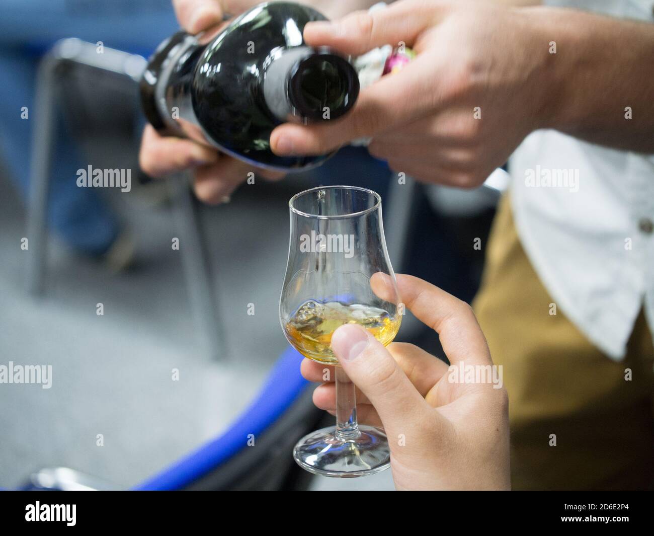 Hand holding a snifter glass filled with whisky, whisky tasting event