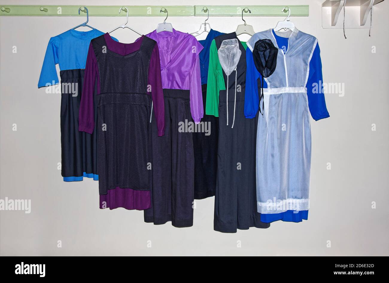 6 Amish girls' dresses hanging, aprons, hats, black, white, green, purple, blue, plain clothing, Lancaster County, Pennsylvania; Bird-in-Hand, PA Stock Photo