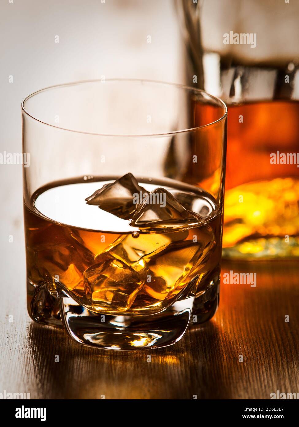 One glass of whiskey on the rocks and a botle on a wooden table Stock ...