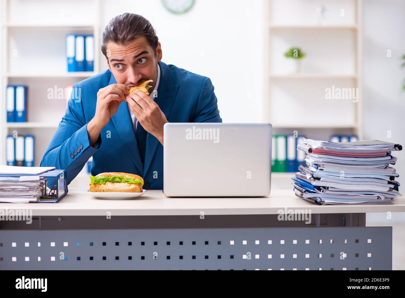 Young employee having breakfast at workplace Stock Photo - Alamy