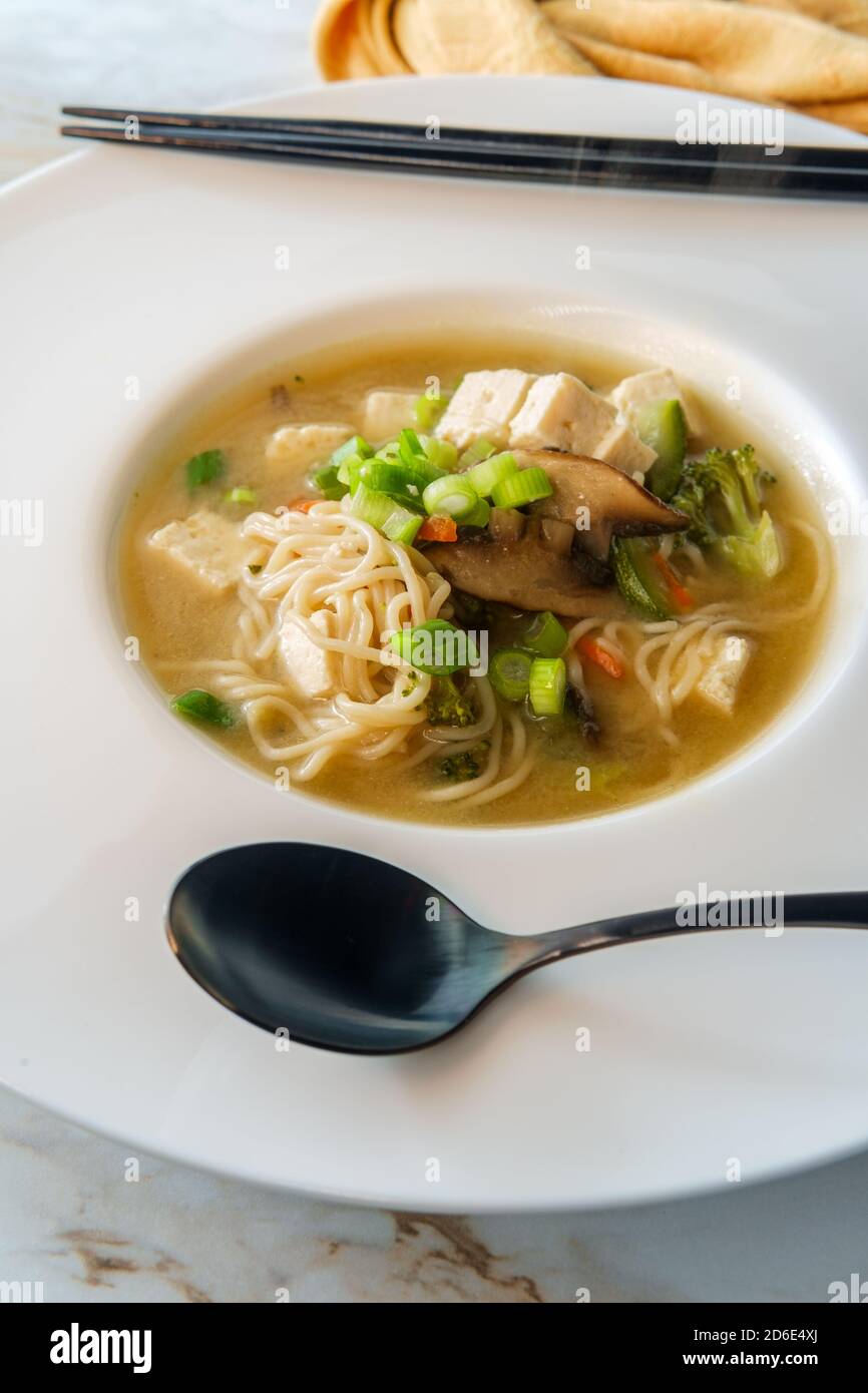 Bowl of loaded Japanese miso soup with noodles tofu julienned carrots and zucchini Stock Photo