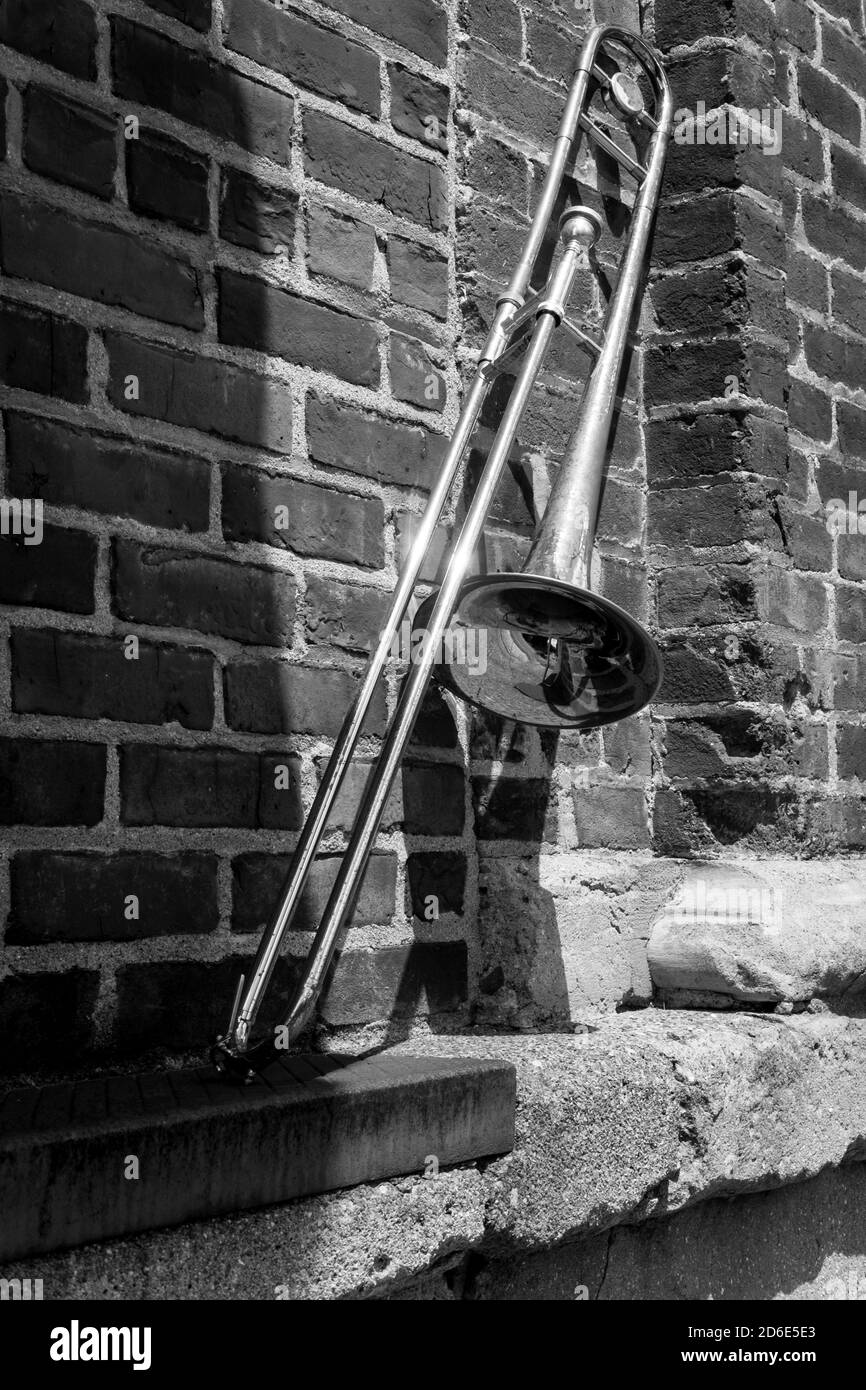 Old rusty vintage trombone leans against brick building outside jazz club Stock Photo