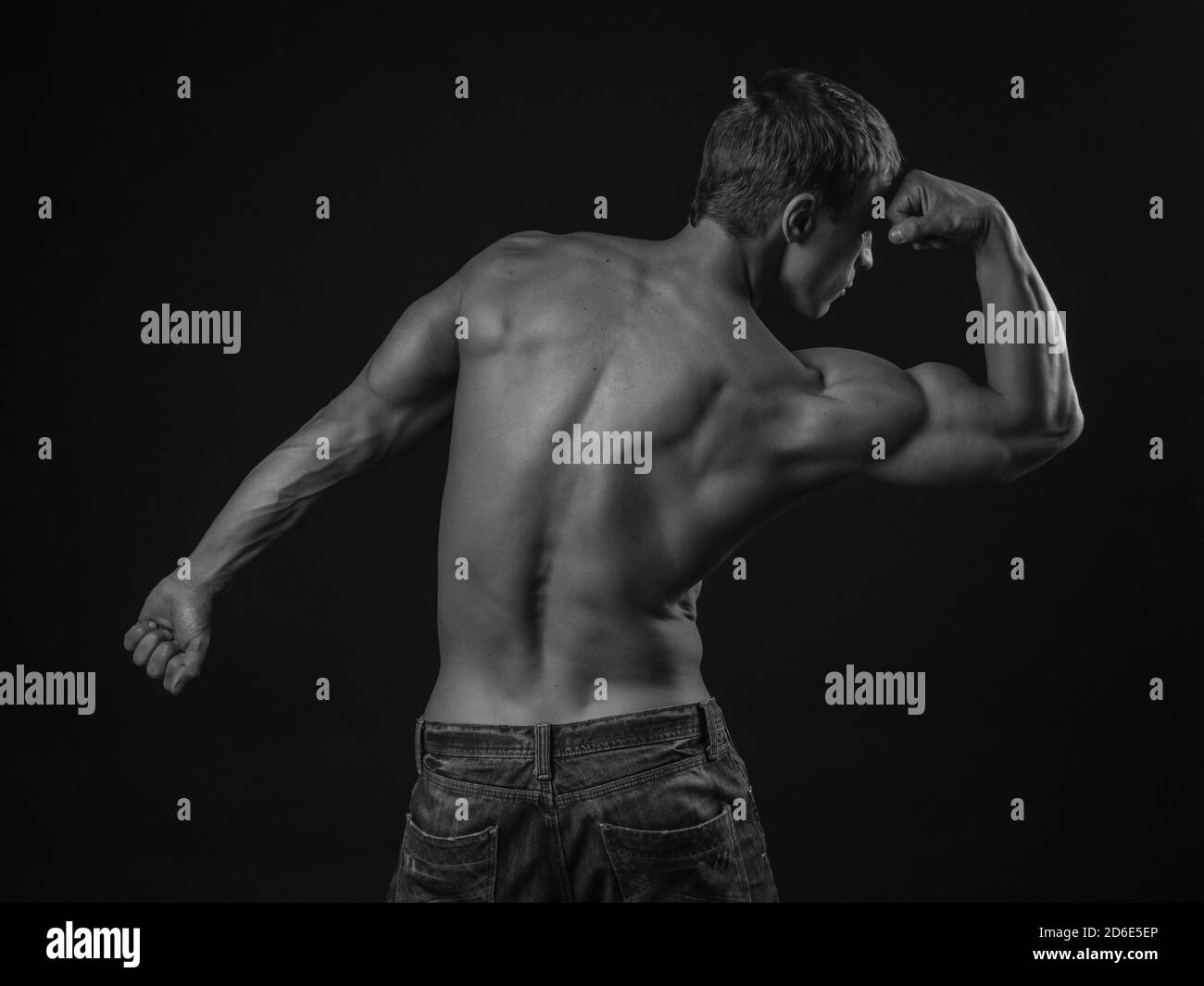 Muscular athlete flexing his arm demonstrating biceps with his back to