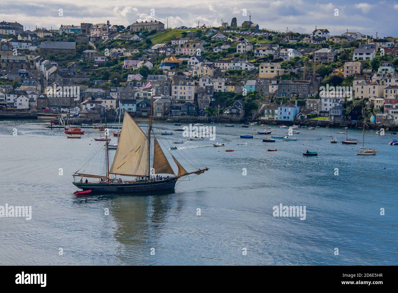 Old ketch leaving Fowey Harbour under sail with Polruan town behind Cornwall England Stock Photo