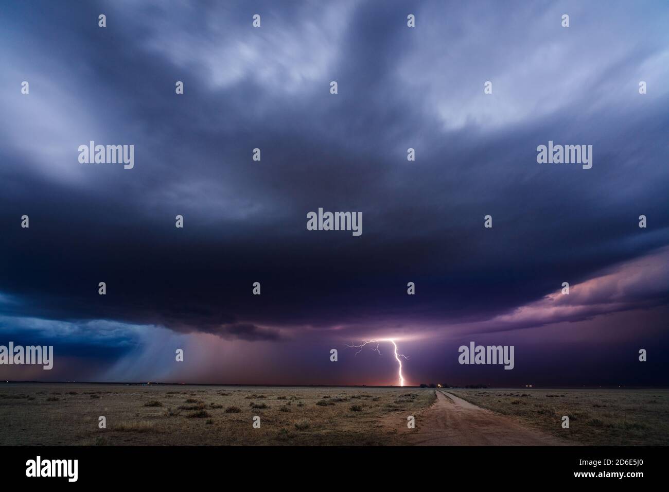 Distant thunderstorm lightning strike over a dirt road and field near Simla, Colorado, USA Stock Photo