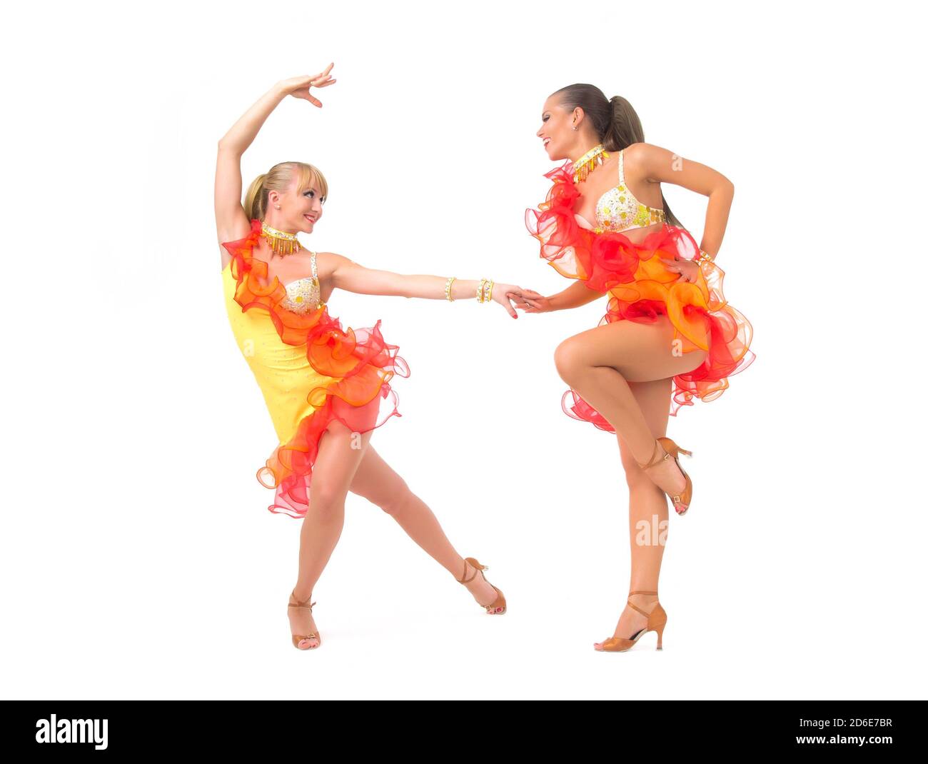 Two female salsa dancers in colorful dresses over white background