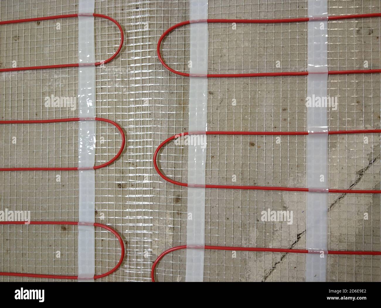 Closeup of concrete and red electrical wires. Electric floor heating