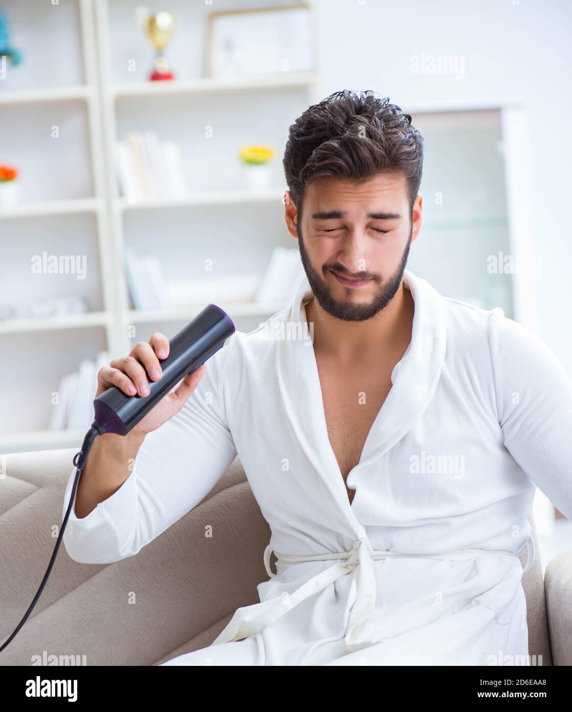 Young man drying hair at home with a hair dryer blower Stock Photo Alamy