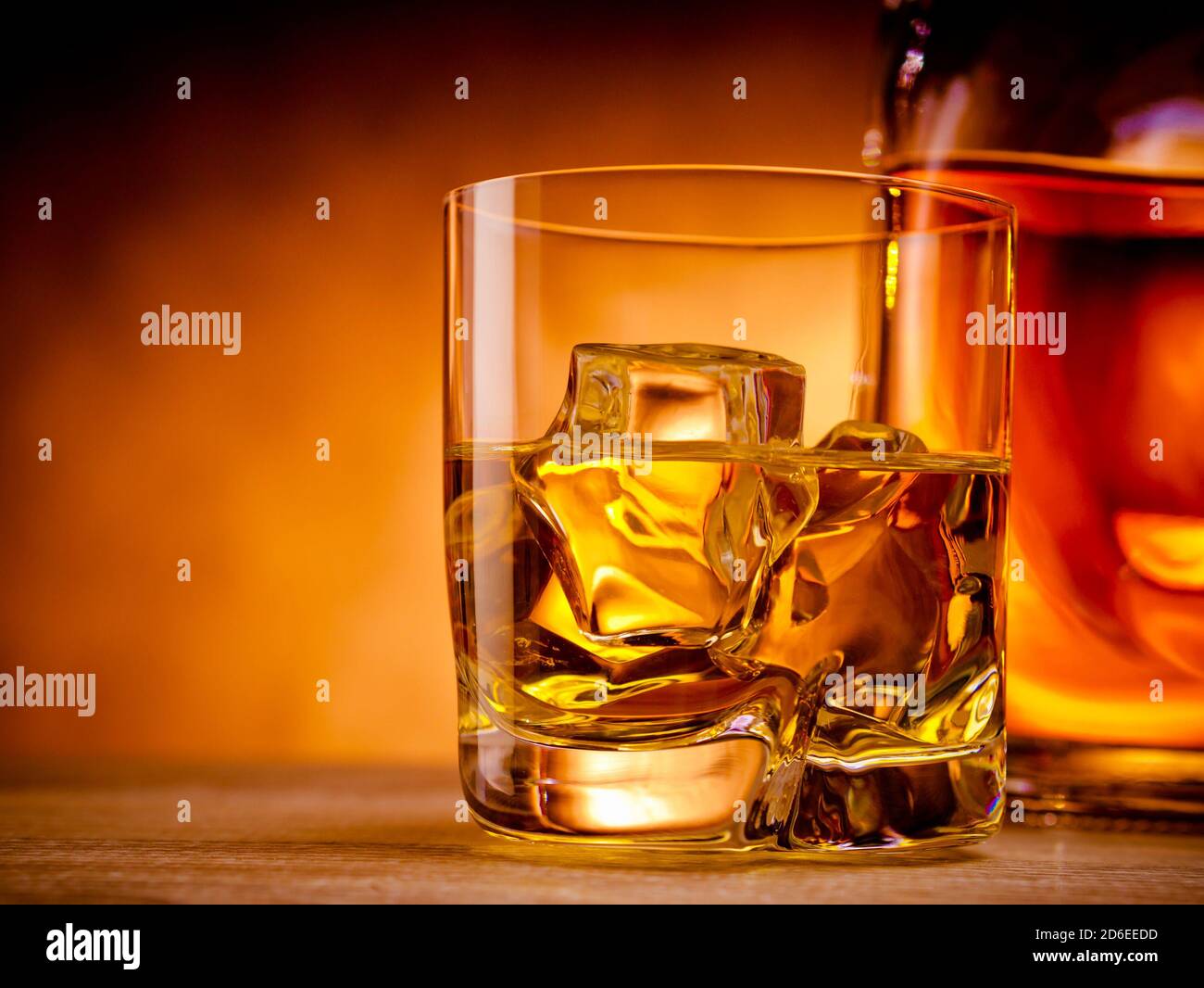 Glass of whiskey on the rocks next to a bottle Stock Photo - Alamy