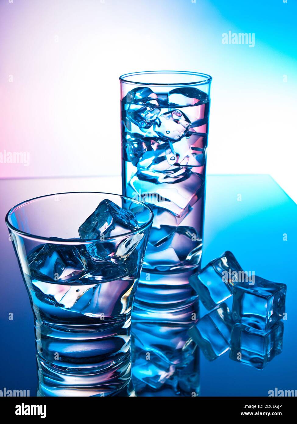 Two cocktails on a reflective surface with ice cubes Stock Photo - Alamy